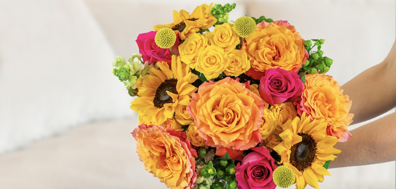 Vibrant bouquet featuring yellow roses, sunflowers, and pink blooms, perfect for celebrations.