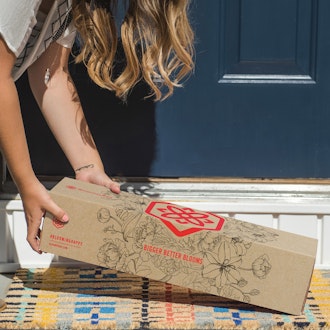 A woman delivers a beautifully packaged floral box to a welcoming front door, enhancing curb appeal.