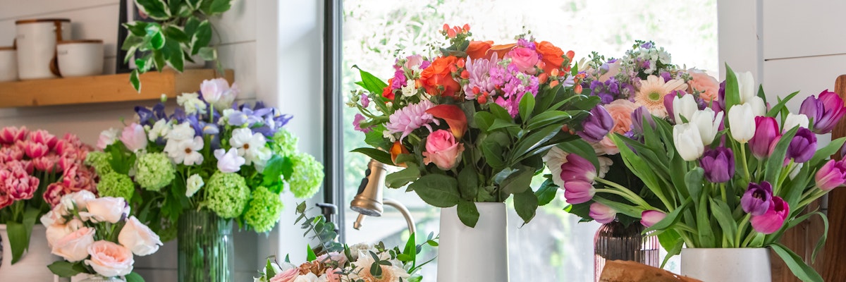 Vibrant flower arrangements featuring tulips, roses, and daisies in a charming floral shop setting.