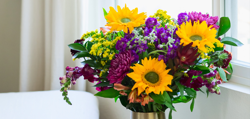 Vibrant bouquet featuring sunflowers, purple blooms, and greenery, brightening up any room.