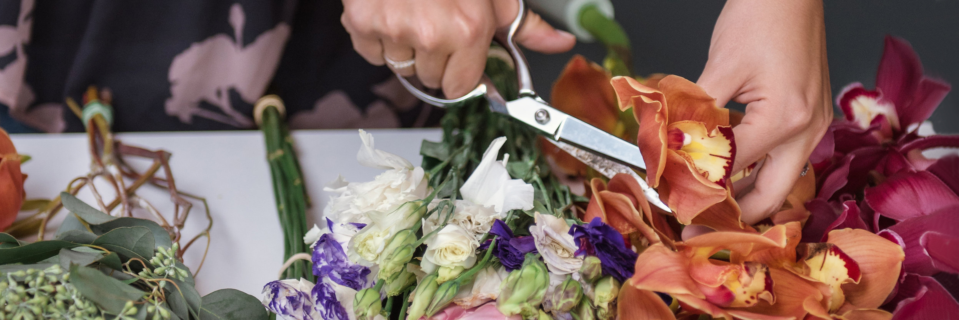 A floral designer skillfully arranging vibrant blooms with scissors for a stunning display.