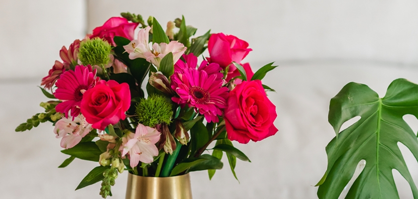 Bright floral arrangement featuring pink roses, gerbera daisies, and green accents in a chic vase.
