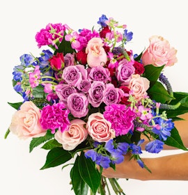 Vibrant bouquet featuring pink and purple roses, carnations, and seasonal greenery.
