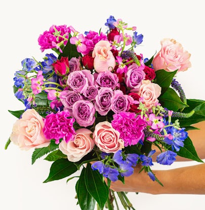 Vibrant bouquet featuring pink and purple roses, carnations, and seasonal greenery.