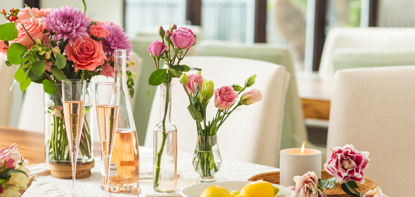 Elegant table setting featuring fresh flowers, champagne glasses, and a candle for a cozy gathering.