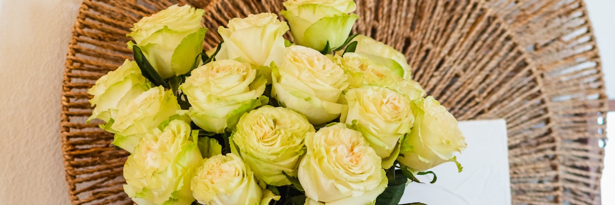 Elegant bouquet of creamy white roses arranged artistically on a rustic woven mat, ideal for decor.
