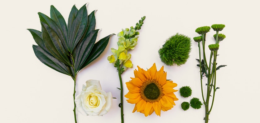 Vibrant floral arrangement with sunflowers, roses, and lush greenery, ideal for decor.
