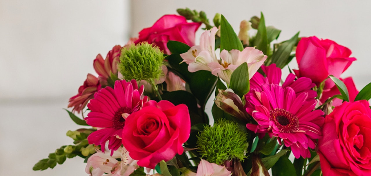 Vibrant floral arrangement featuring pink roses, gerbera daisies, and green accents.