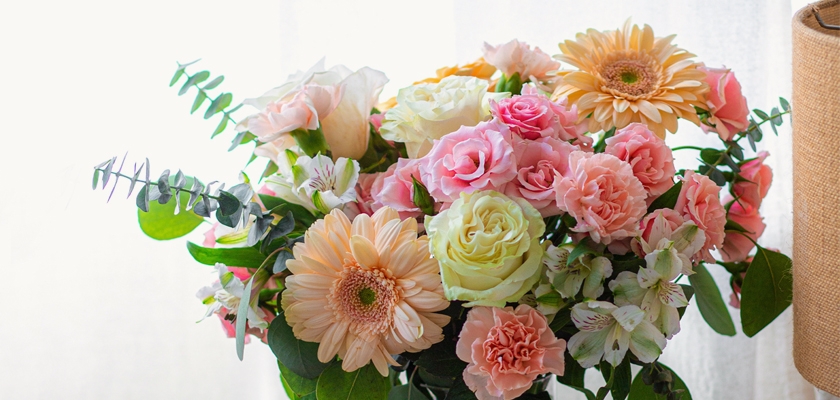Bright floral arrangement featuring pink roses, cheerful gerbera daisies, and lush greenery.
