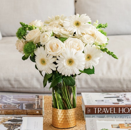 Elegant floral arrangement with white roses and gerbera daisies in a chic vase.