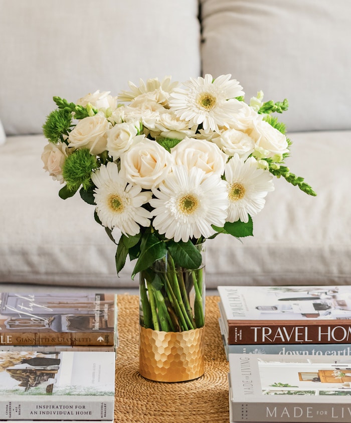 Elegant floral arrangement with white roses and gerbera daisies in a chic vase.