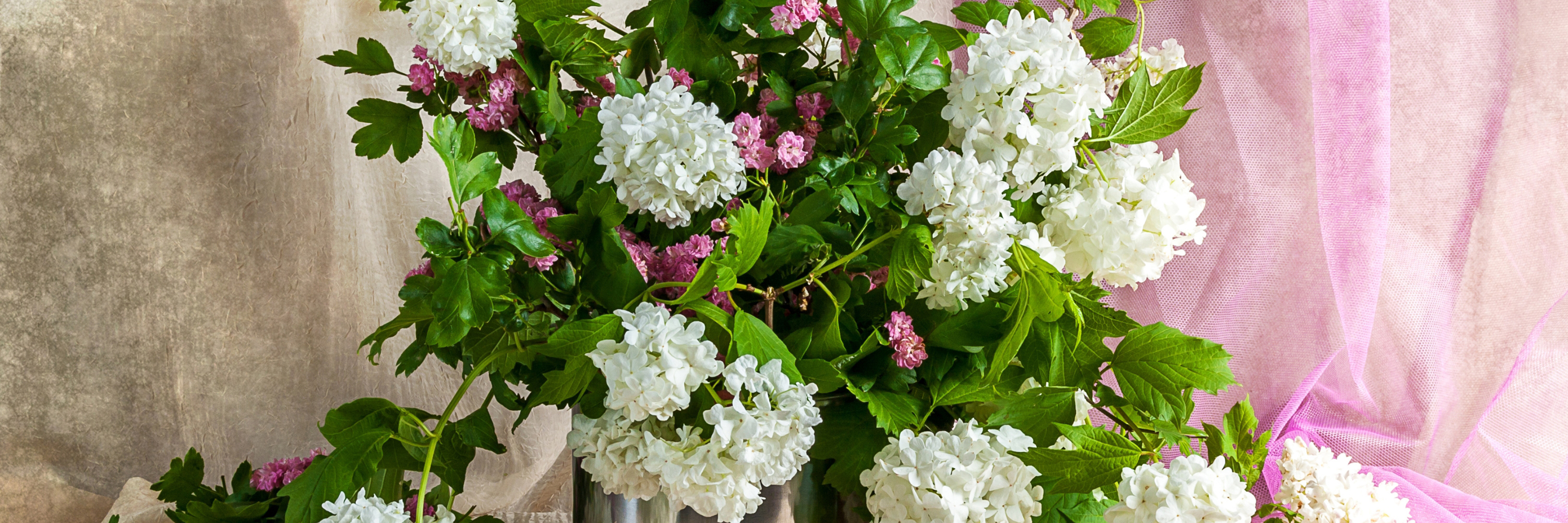 Lush white and pink floral arrangement featuring vibrant leaves, perfect for elegant decor.