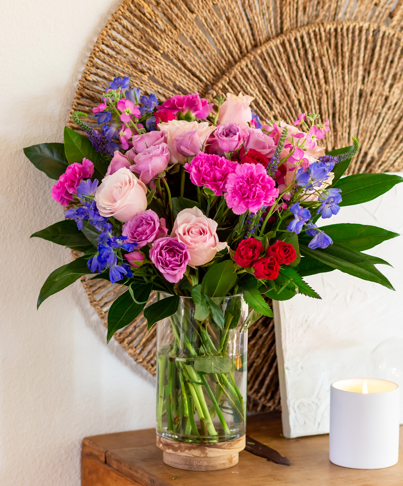 Vibrant floral arrangement in a glass vase featuring pink roses and colorful blooms.
