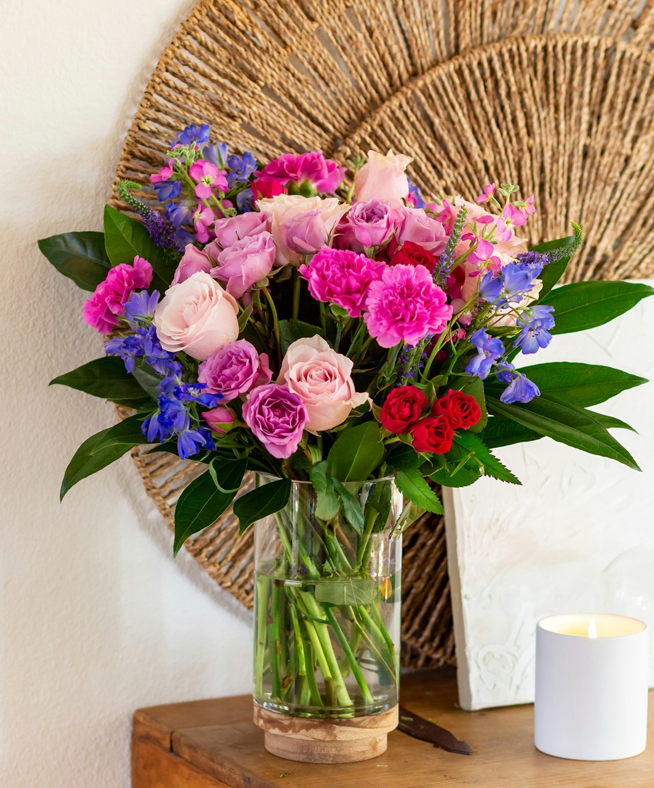 Vibrant floral arrangement in a glass vase featuring pink roses and colorful blooms.