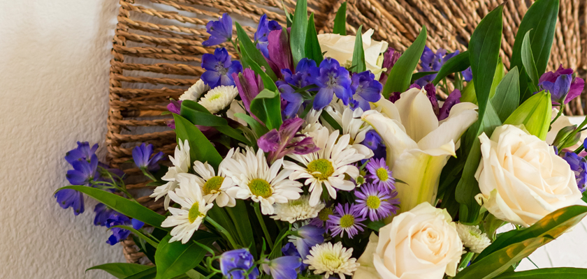 Vibrant floral arrangement featuring white roses, daisies, and purple blooms in a stylish display.