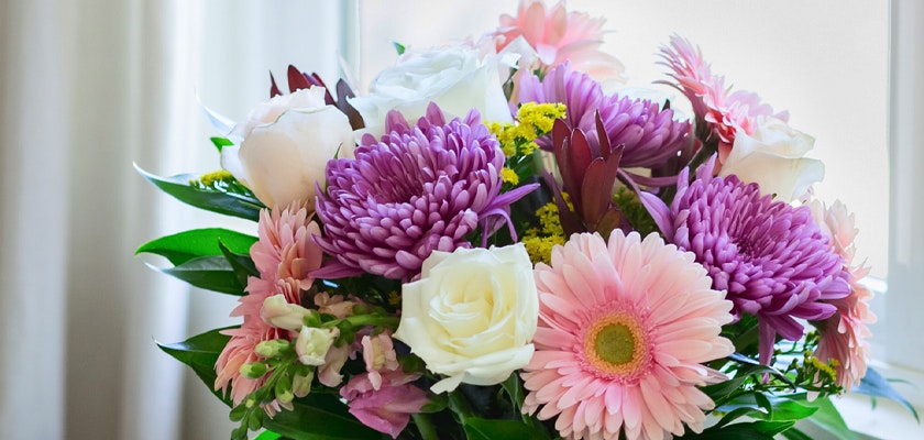 Vibrant floral arrangement featuring pink gerbera daisies, white roses, and purple chrysanthemums.