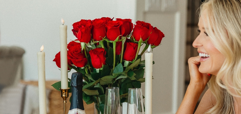 A stunning arrangement of red roses beside elegant candles, complementing a joyful celebration.