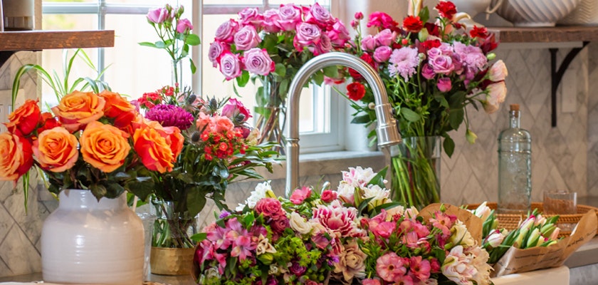 Colorful floral arrangement featuring roses and assorted blooms in a bright kitchen setting.