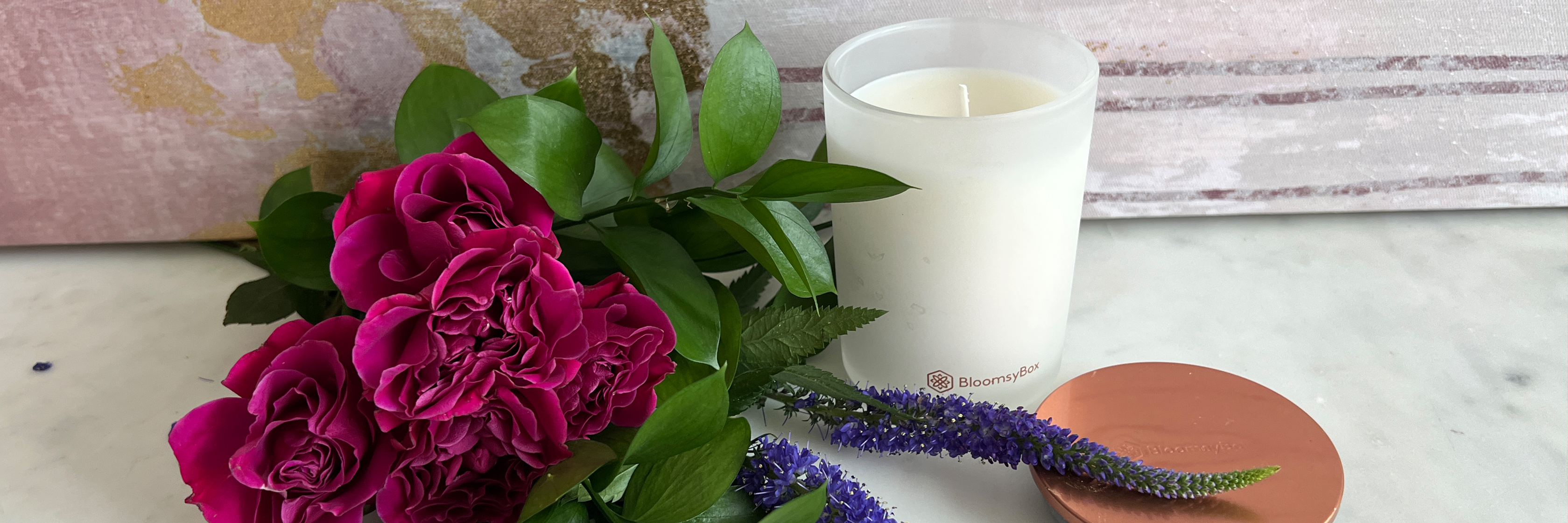 Vibrant pink roses beside a scented candle, creating a cozy and inviting atmosphere.