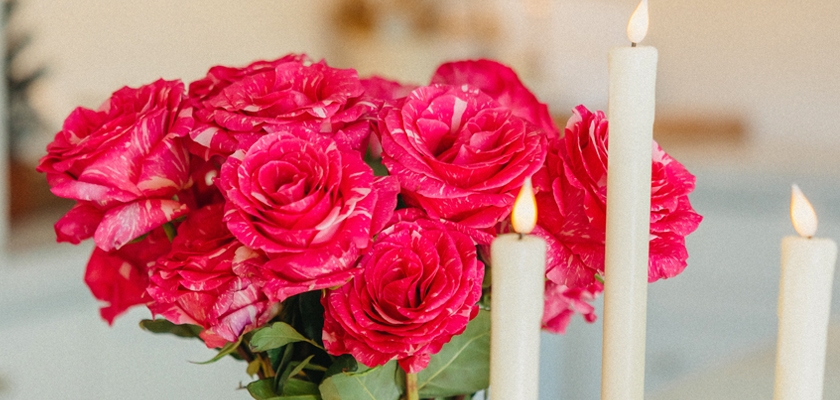 Vibrant pink roses in a lovely arrangement with white candles, creating a romantic ambiance.