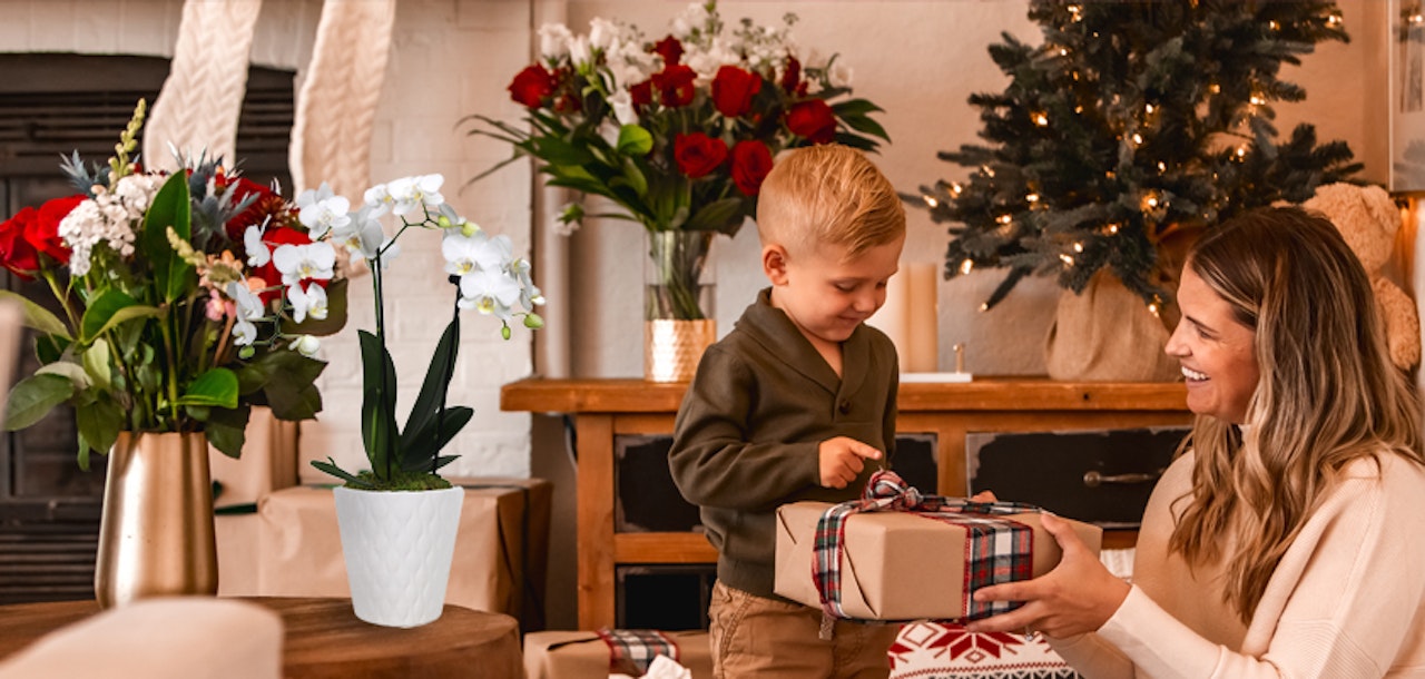 A cheerful holiday scene featuring a woman and child exchanging gifts by a festive tree.