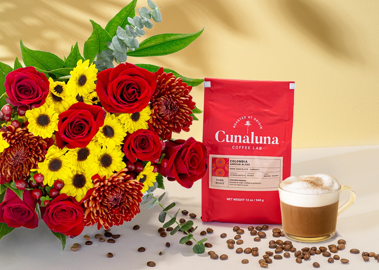 Vibrant floral bouquet with red roses and yellow blooms beside fresh coffee, ideal for gifts.