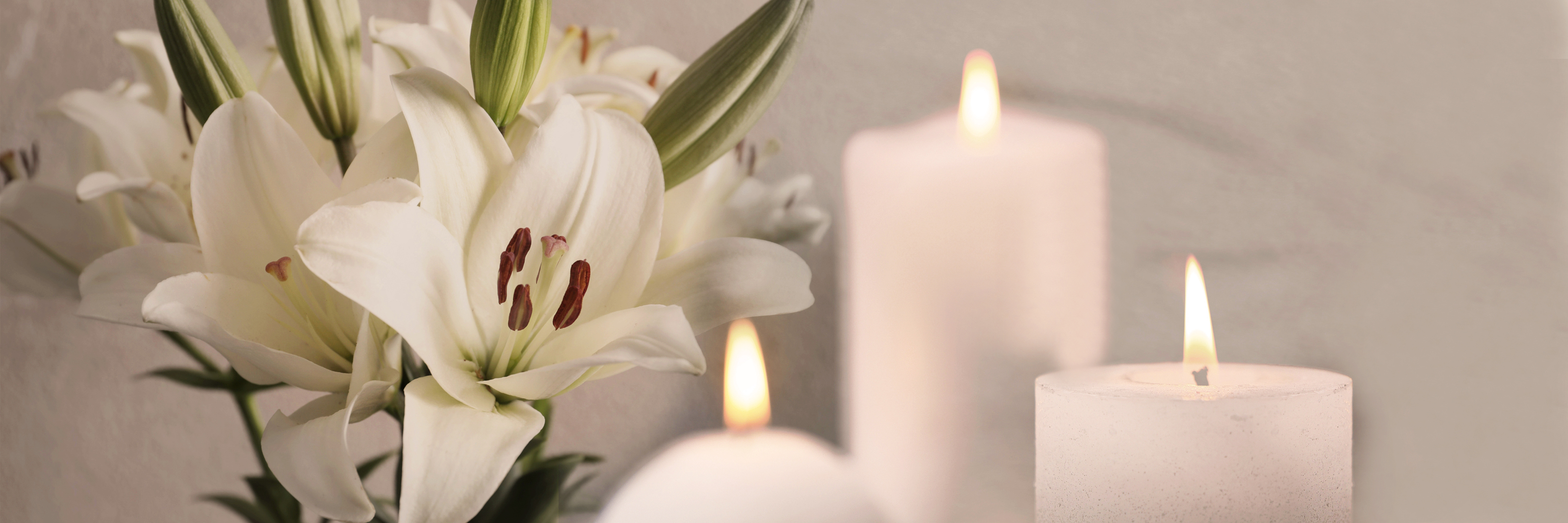 Elegant white lilies surrounded by softly glowing candles create a serene ambiance.