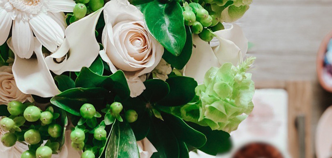 Elegant floral arrangement featuring soft pink roses, green accents, and delicate white blooms.