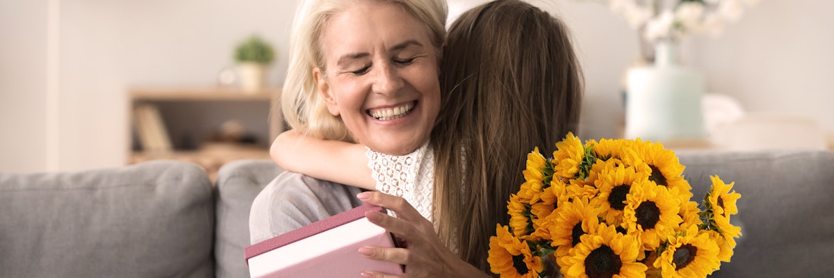 A joyful grandmother receives a surprise gift and sunflower bouquet from her granddaughter.