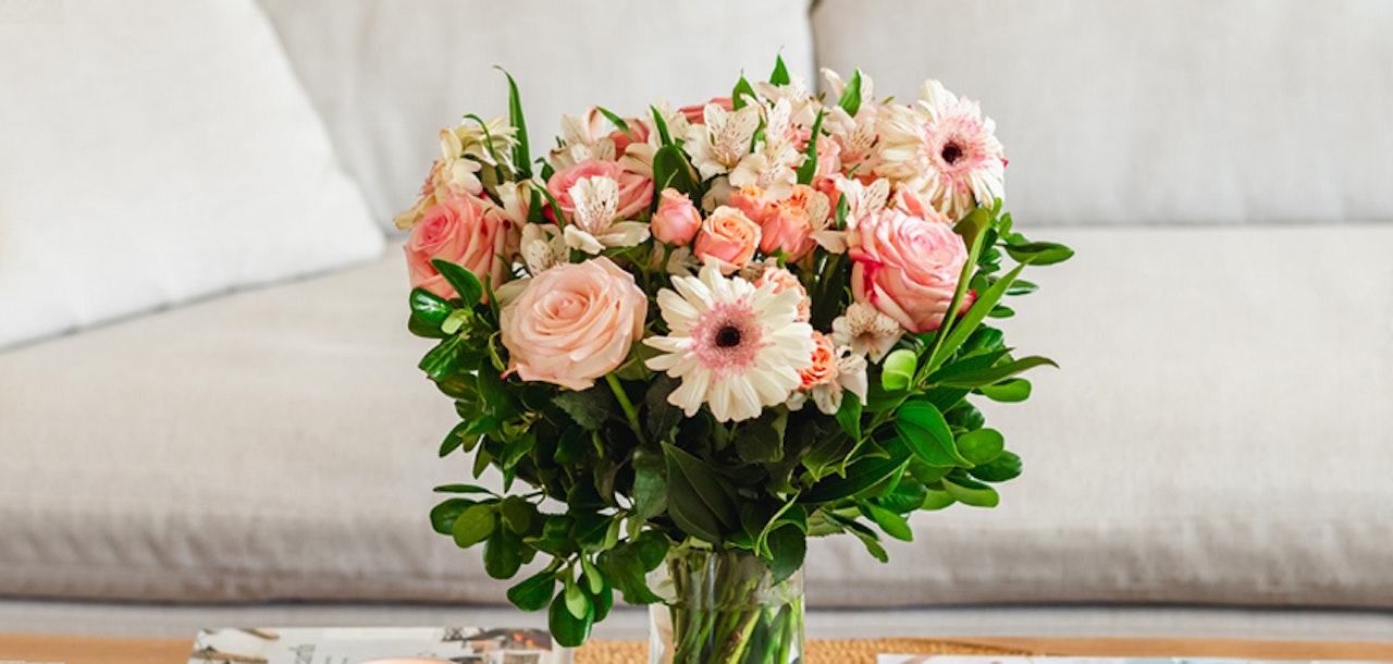 Charming bouquet of pink roses and daisies in a glass vase, perfect for brightening any home décor.