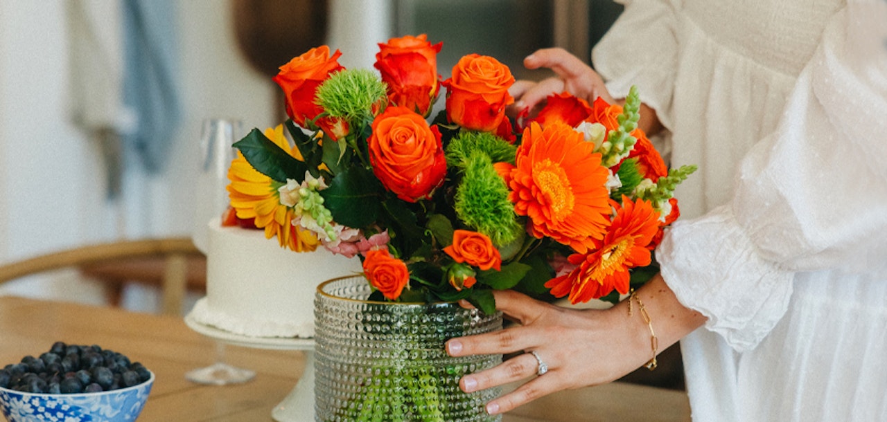 Vibrant floral arrangement featuring orange roses and yellow gerberas in a stylish vase.