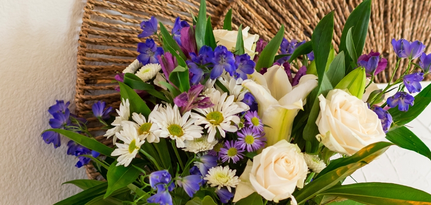 A vibrant floral arrangement featuring white roses, daisies, and purple blooms in a natural setting.