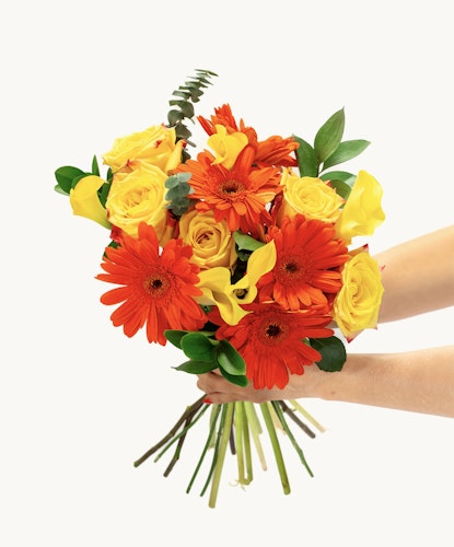 Vibrant bouquet featuring orange gerbera daisies and yellow roses, elegantly held.