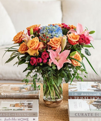 Vibrant floral arrangement featuring roses, hydrangeas, and lilies in a chic glass vase.