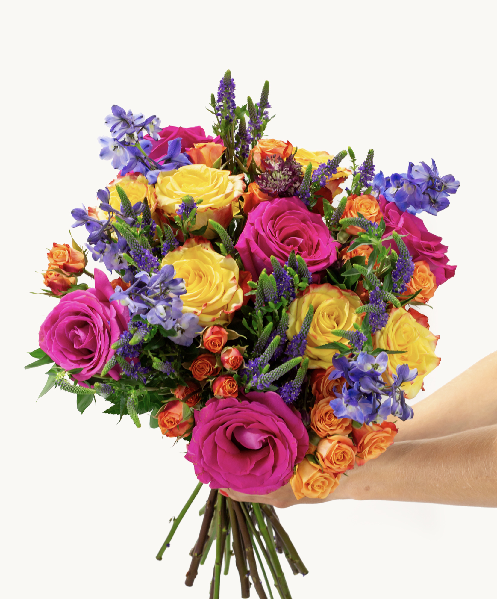Vibrant bouquet featuring bright roses, yellow blooms, and purple flowers in a hand-held display.
