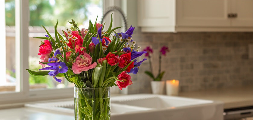 Vibrant floral bouquet featuring pink carnations and blue irises in a modern kitchen setting.