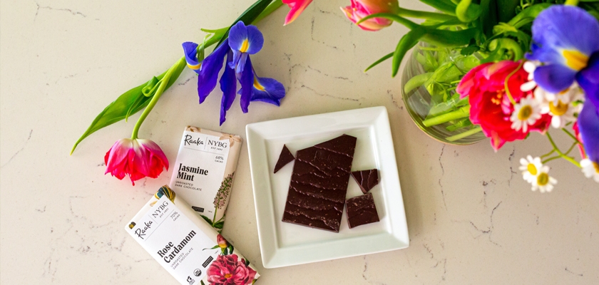 Elegant arrangement of colorful flowers beside artisan chocolate bars on a marble surface.