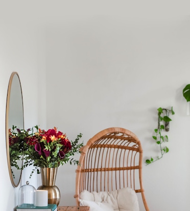 Elegant floral arrangement in a gold vase beside a mirror, enhancing a cozy living space.