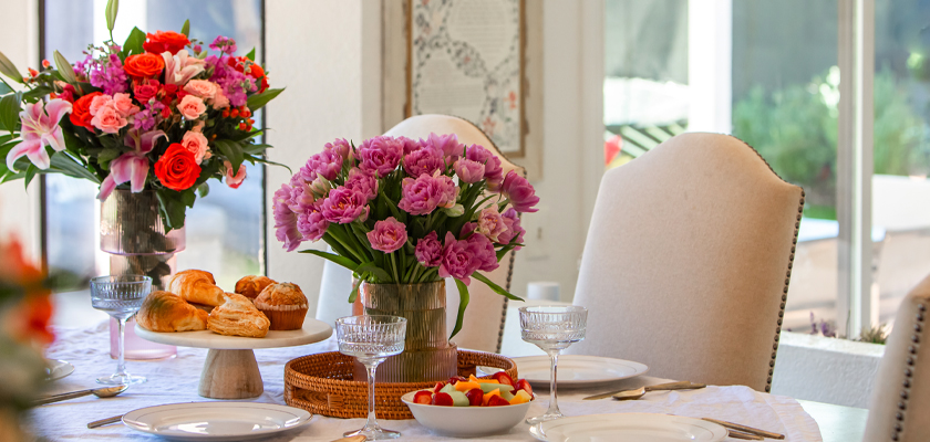 A beautifully set table featuring vibrant floral arrangements and delicious pastries.