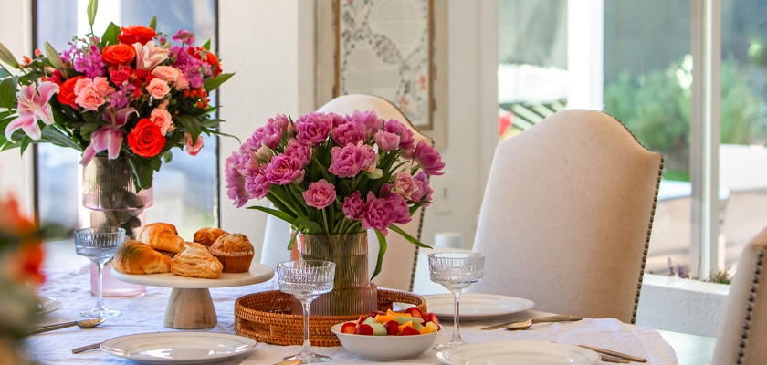 A beautifully set table featuring vibrant floral arrangements and delicious pastries.