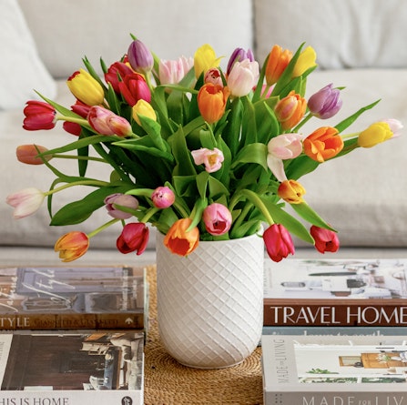 Vibrant bouquet of multi-colored tulips in a textured vase, perfect for spring decor.