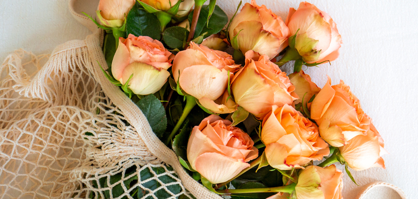 A lovely arrangement of peach roses nestled in a natural mesh bag, perfect for gifts and decor.