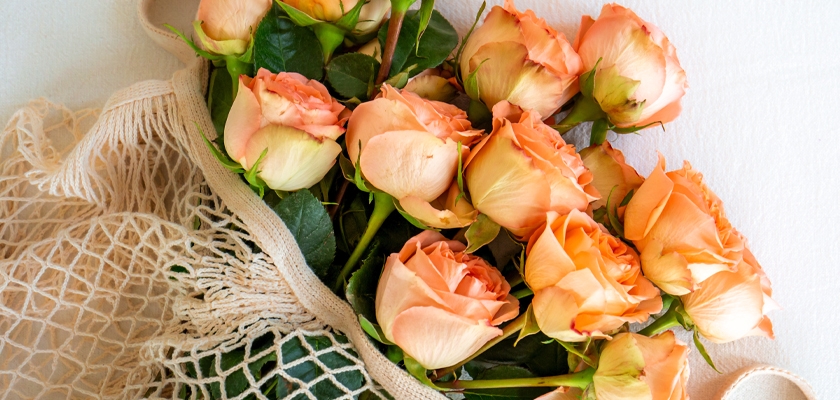 A lovely arrangement of peach roses nestled in a natural mesh bag, perfect for gifts and decor.