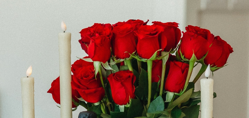 Elegant bouquet of vibrant red roses surrounded by white candles, perfect for romantic settings.