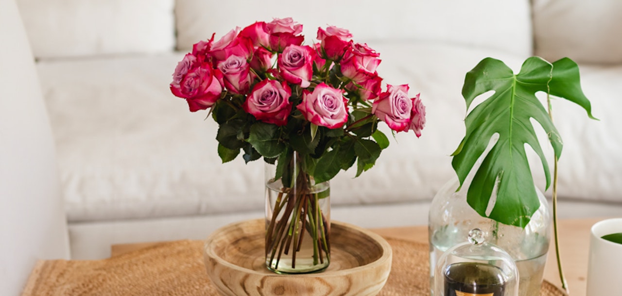 A vibrant bouquet of pink roses in a glass vase, enhancing a cozy living room setting.