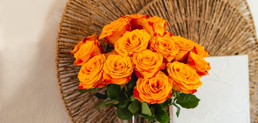 Vibrant bouquet of yellow and orange roses with lush green leaves, perfect for brightening any room.