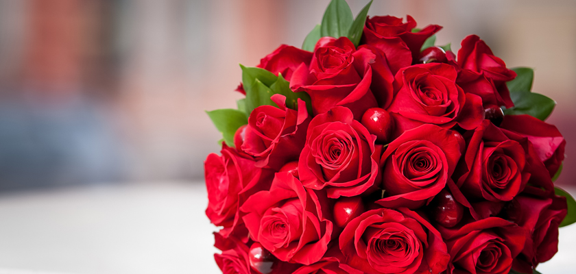 Vibrant bouquet of fresh red roses, elegantly arranged with green leaves for a striking display.