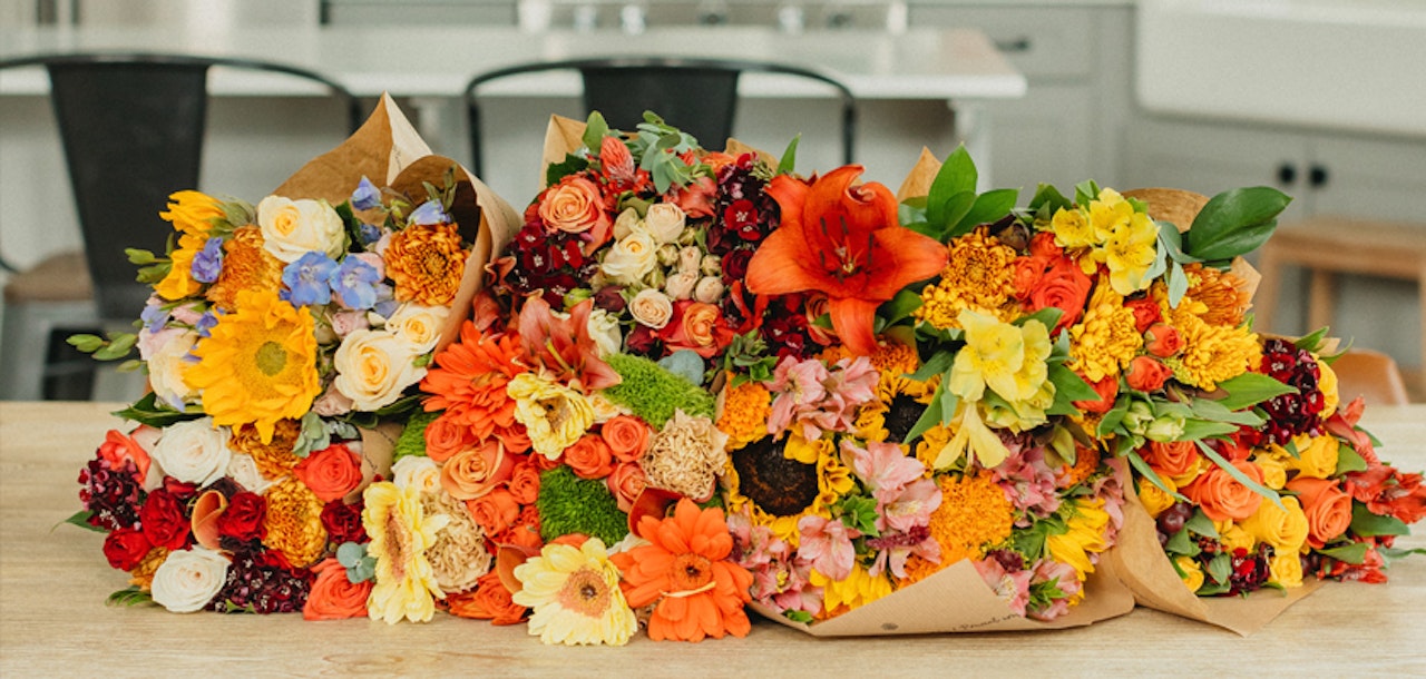 Vibrant mixed flower bouquets featuring sunflowers, lilies, and colorful blooms arranged on a table.