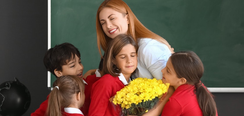 A joyful teacher receives a vibrant bouquet of yellow flowers from her cheerful students.