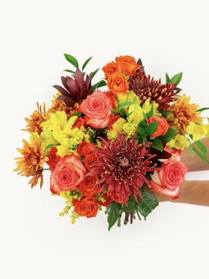 Vibrant floral bouquet featuring roses, lilies, and chrysanthemums in warm autumn tones.